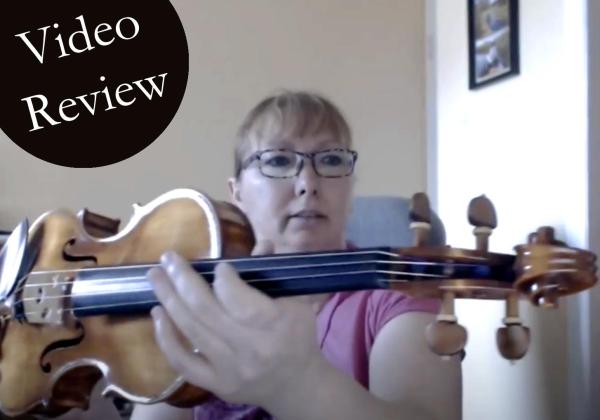 Woman holding a violin up to the camera, text reads "video review"