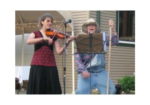Woman and her mother dressed as hillbillies playing fiddle and washtub bass