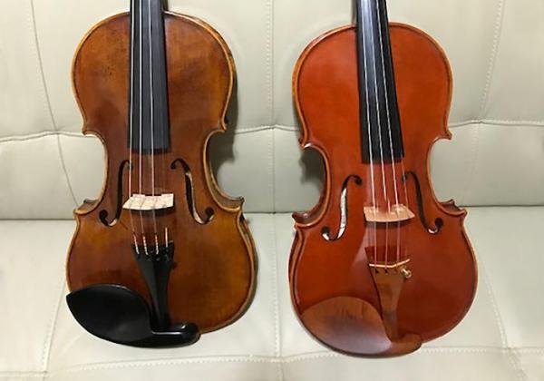 A Migiel and Dimitrov violin sit side by side on a leather couch