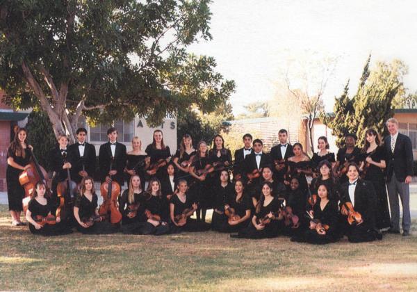 High school orchestra standing outside, with the teacher and Rhiannon on the far right