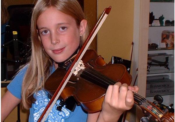 Blonde teen girl playing violin smirks at the camera