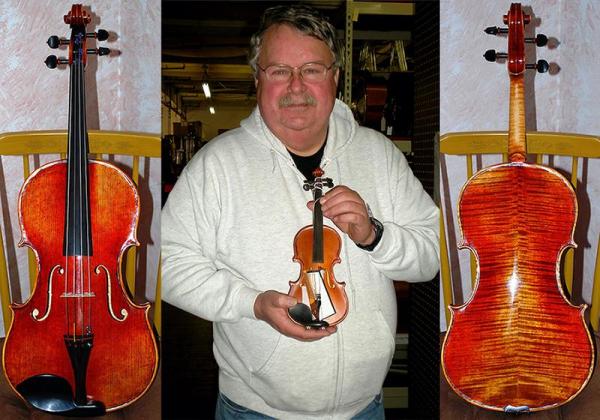 Jolly heavy-set middle-aged man holding a teensy, tiny violin and smiling. Also a violin front and back to the sides of the image.