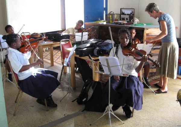 Teacher and classroom full of teens learning to play violin as a group