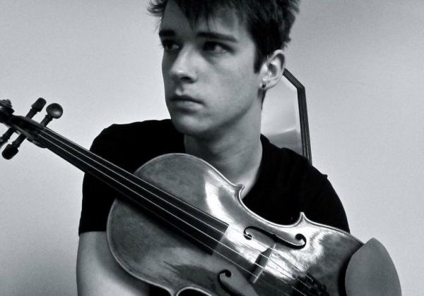 Black and white photo of Adam in a black t shirt holding his violin