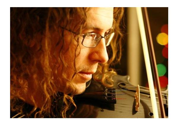 Closeup of man with curly hair and glasses playing violin