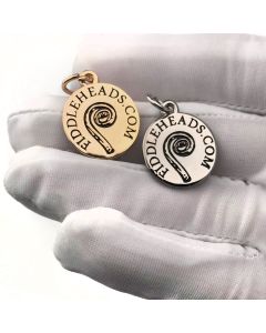 White gloved hand holding gold and silver fiddleheads logo charms