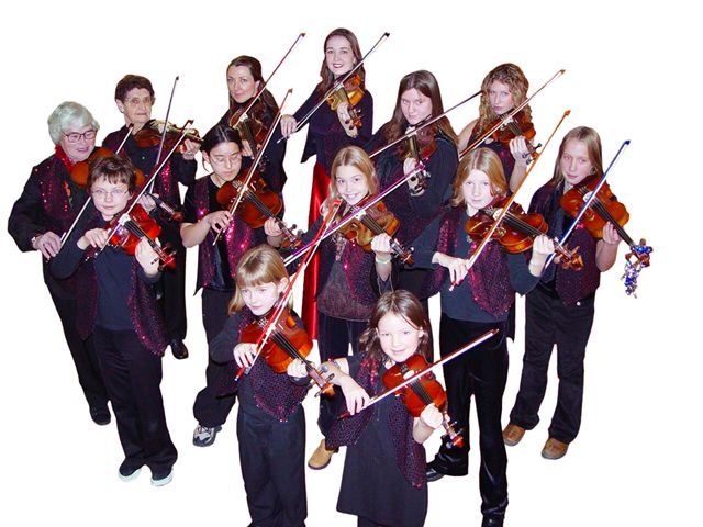Young Rhiannon and her students of all ages playing the violin in matching red and black outfits