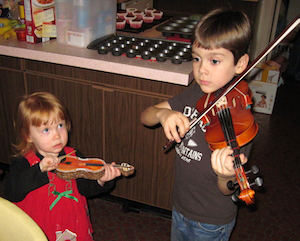 Toddler with a fake violin and her older brother playing a violin