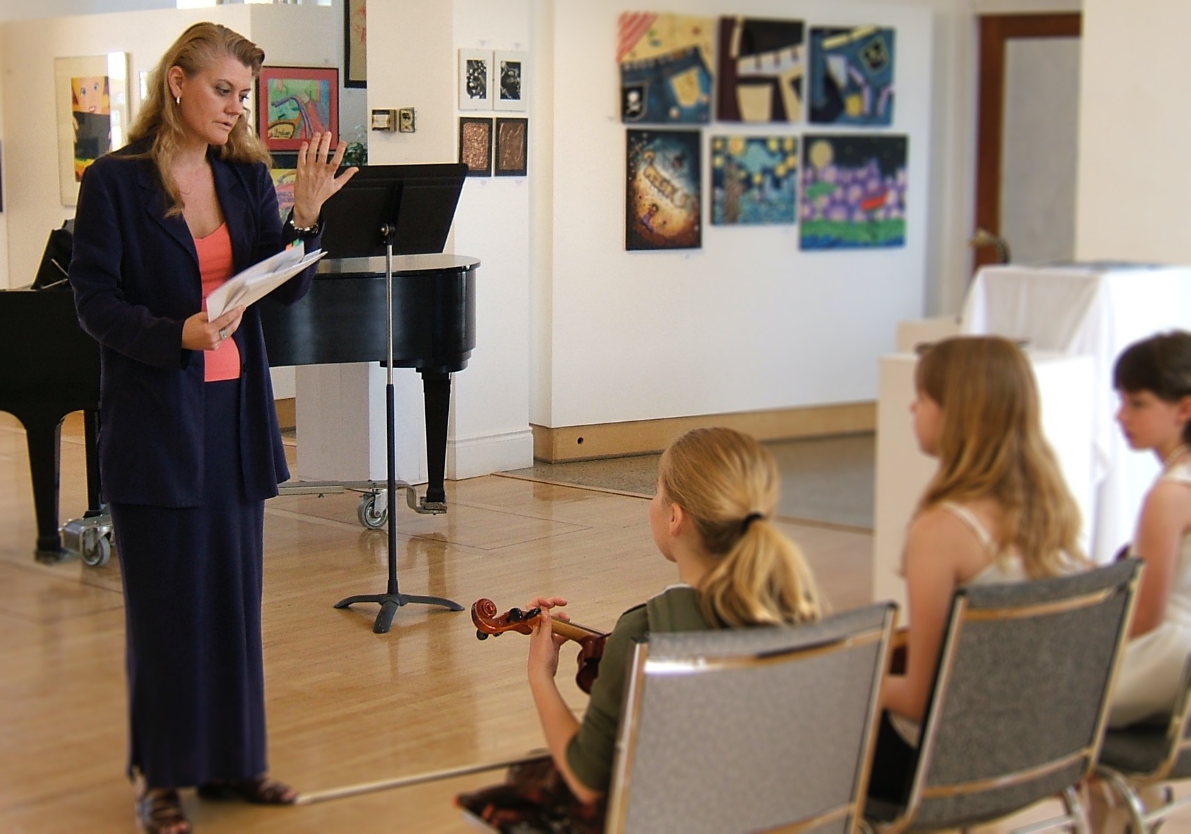 Violin adjudicator talking to three young violin students in an art gallery