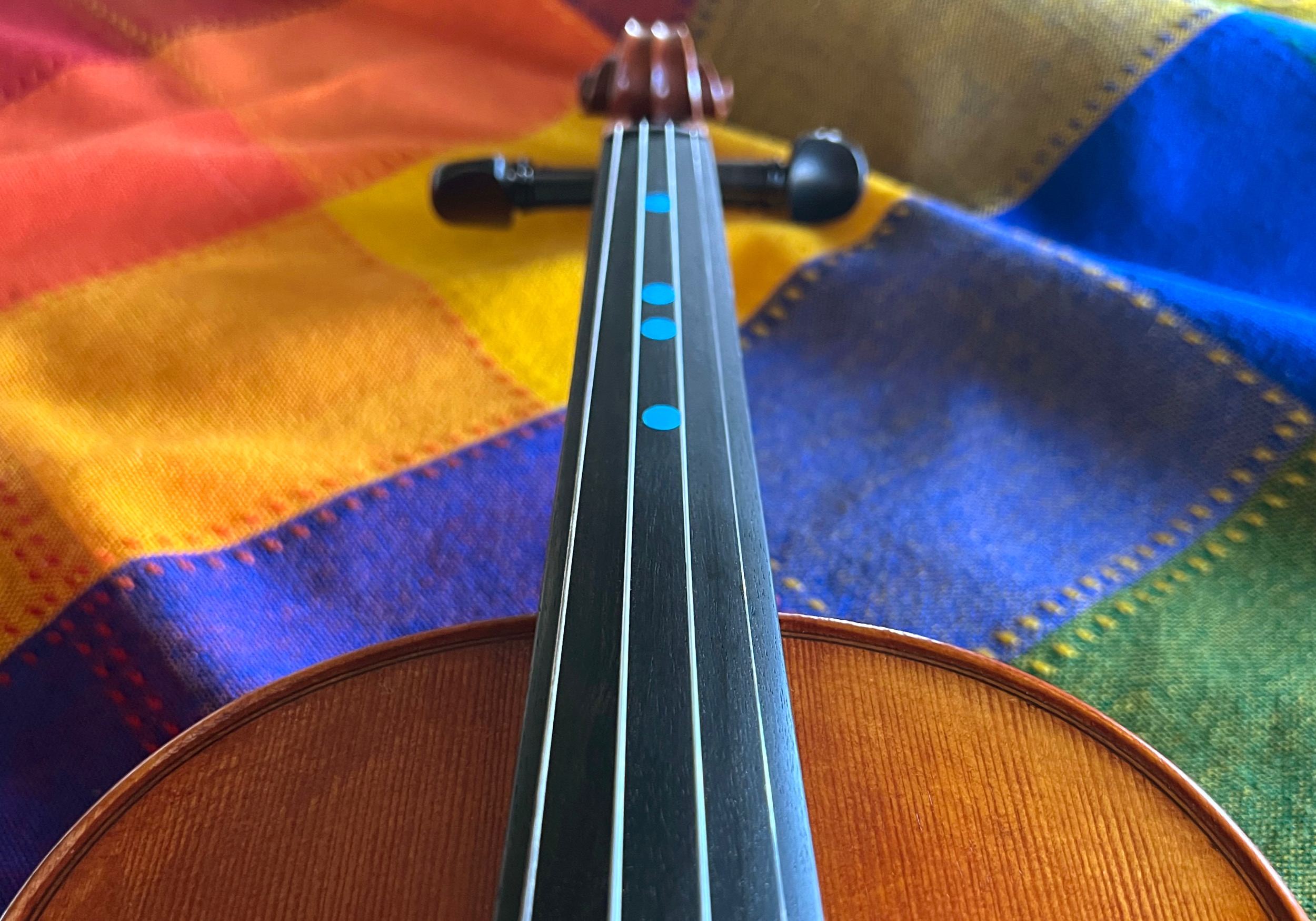 Violin's fingerboard and strings with four small circular blue dot stickers in a row