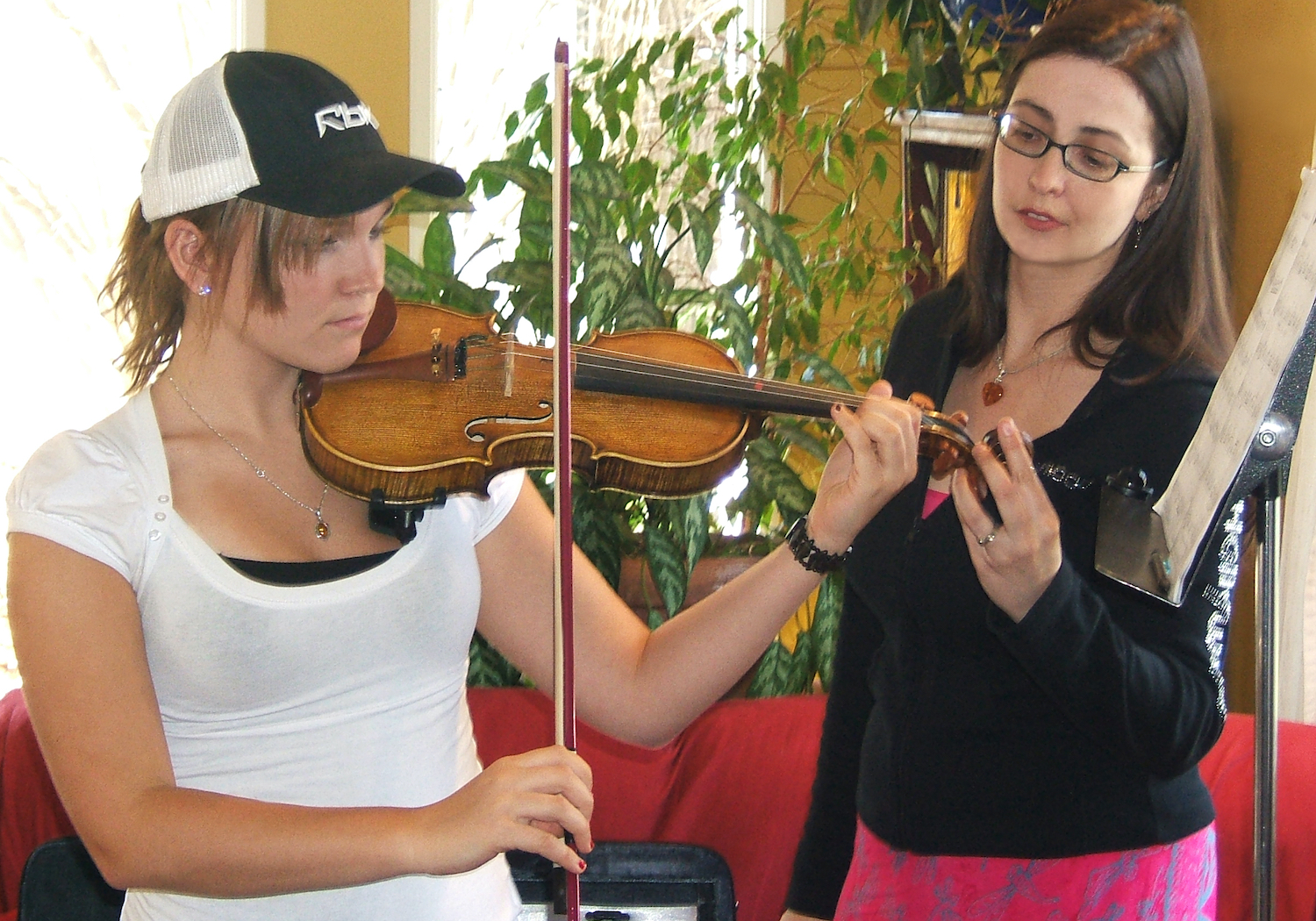 A young Rhiannon helping a student with a violin