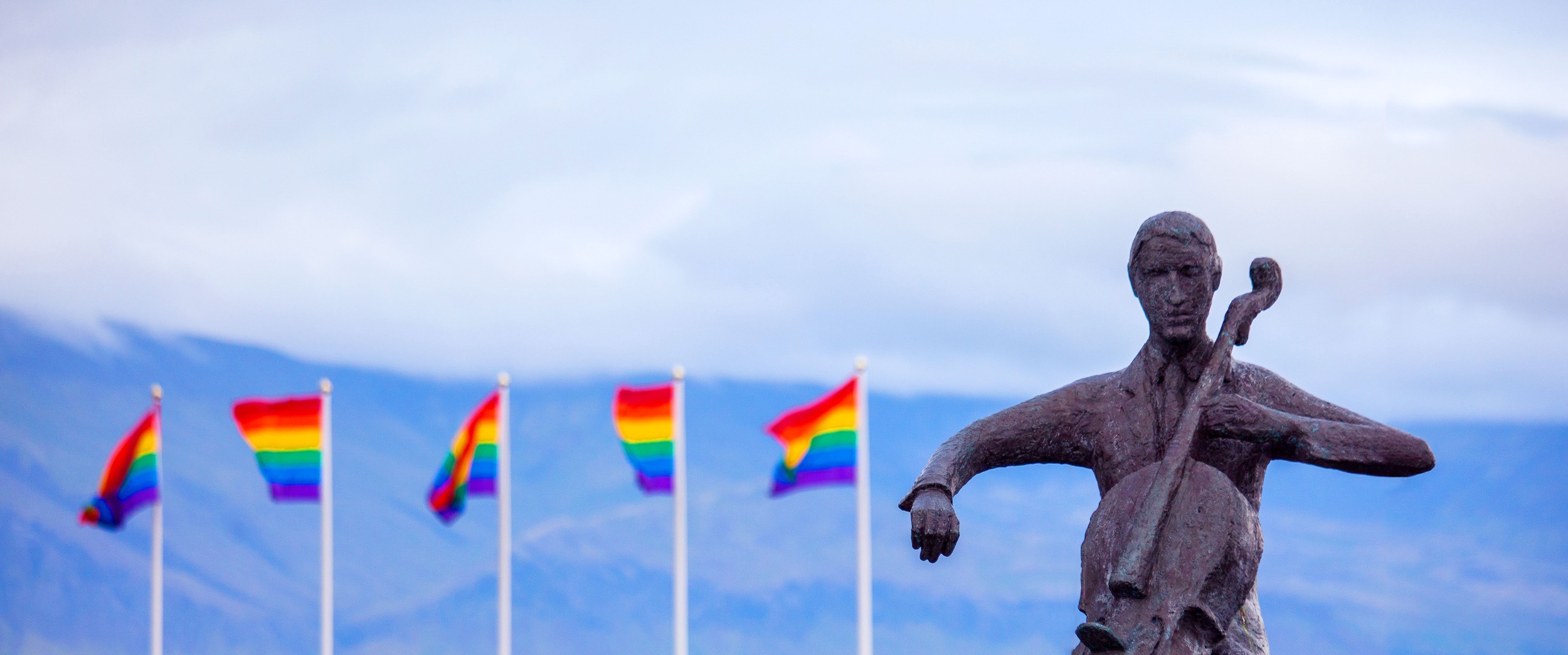 pride flags behind statue of a cellist