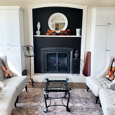 Fiddleheads' ornate heritage decorated studio main space with white wingback chairs, fireplace and violins