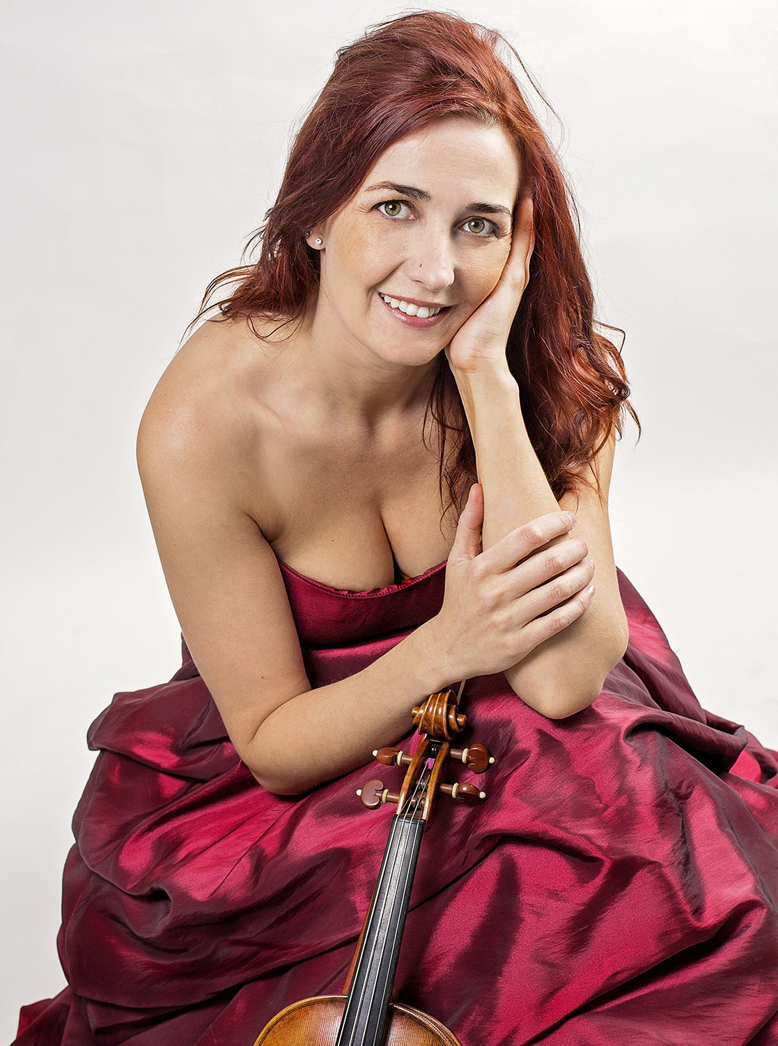 Rhiannon sitting in a red dress with her violin