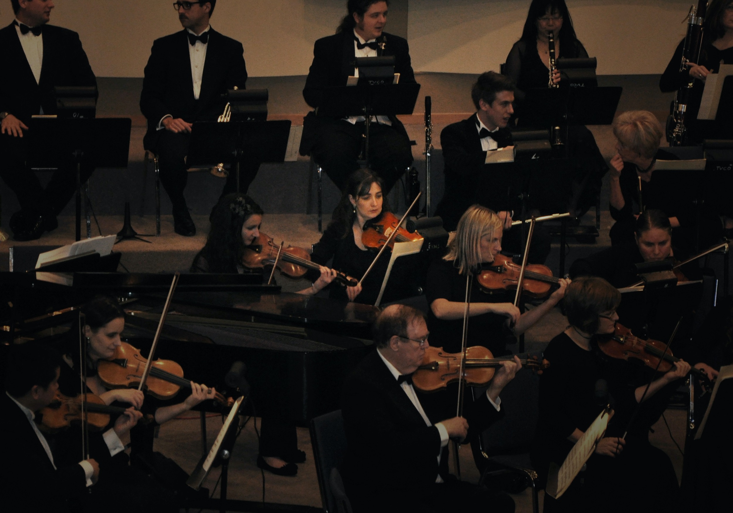 rhiannon in the violin section of a symphony surrounded by other musicians in black formal wear