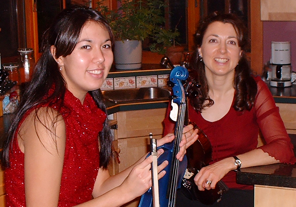 Mother and teen daughter holding their violins at a Christmas house recital