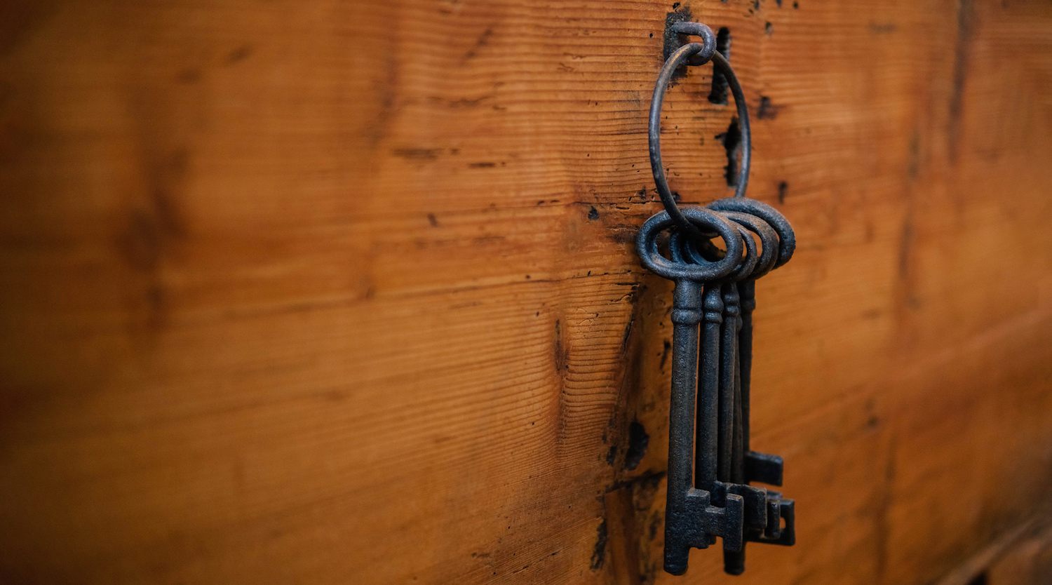antique keys hanging on hook on wooden wall