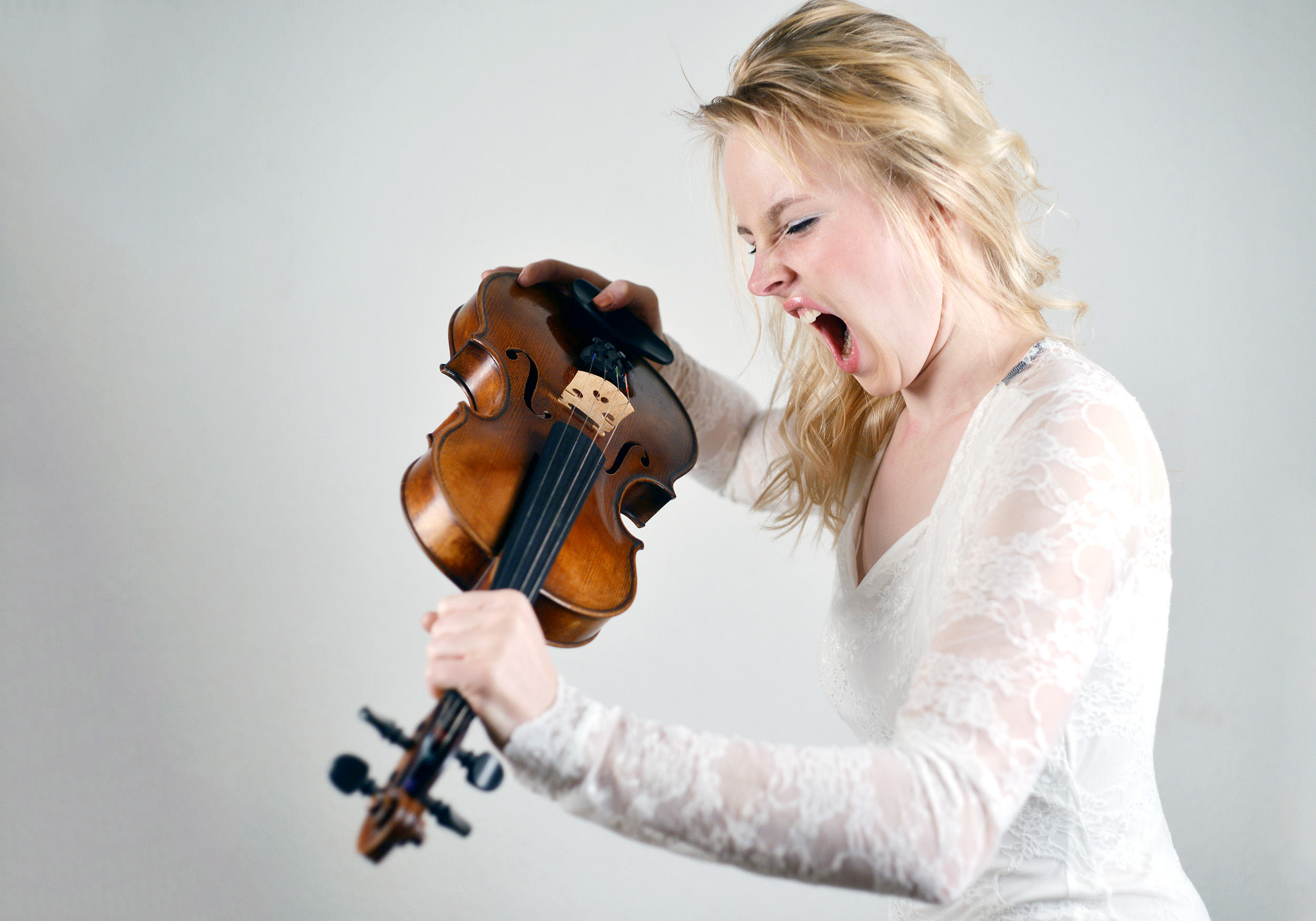 Woman looking inside f-hole of violin at label and screaming at it