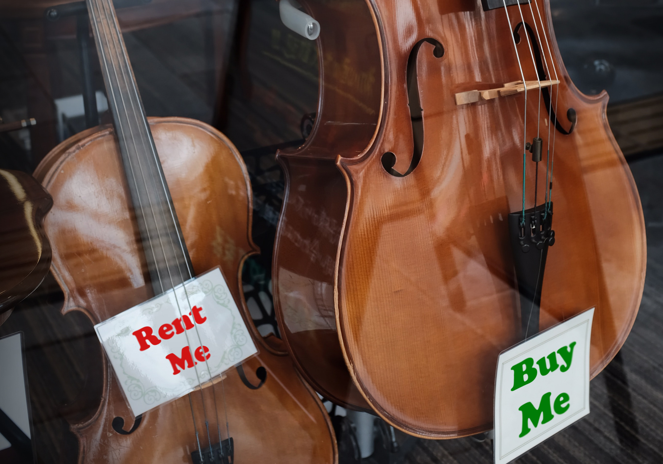 violin and cello in shop window with rent me and buy me signs