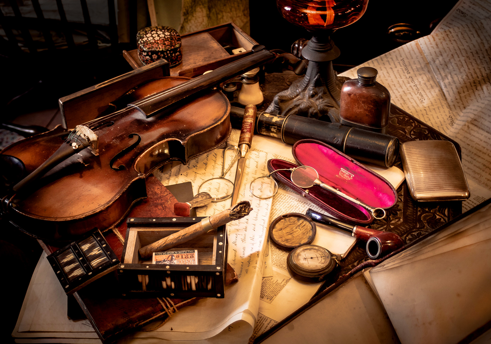 Antique violin on dimly-lit desk with old articles and objects