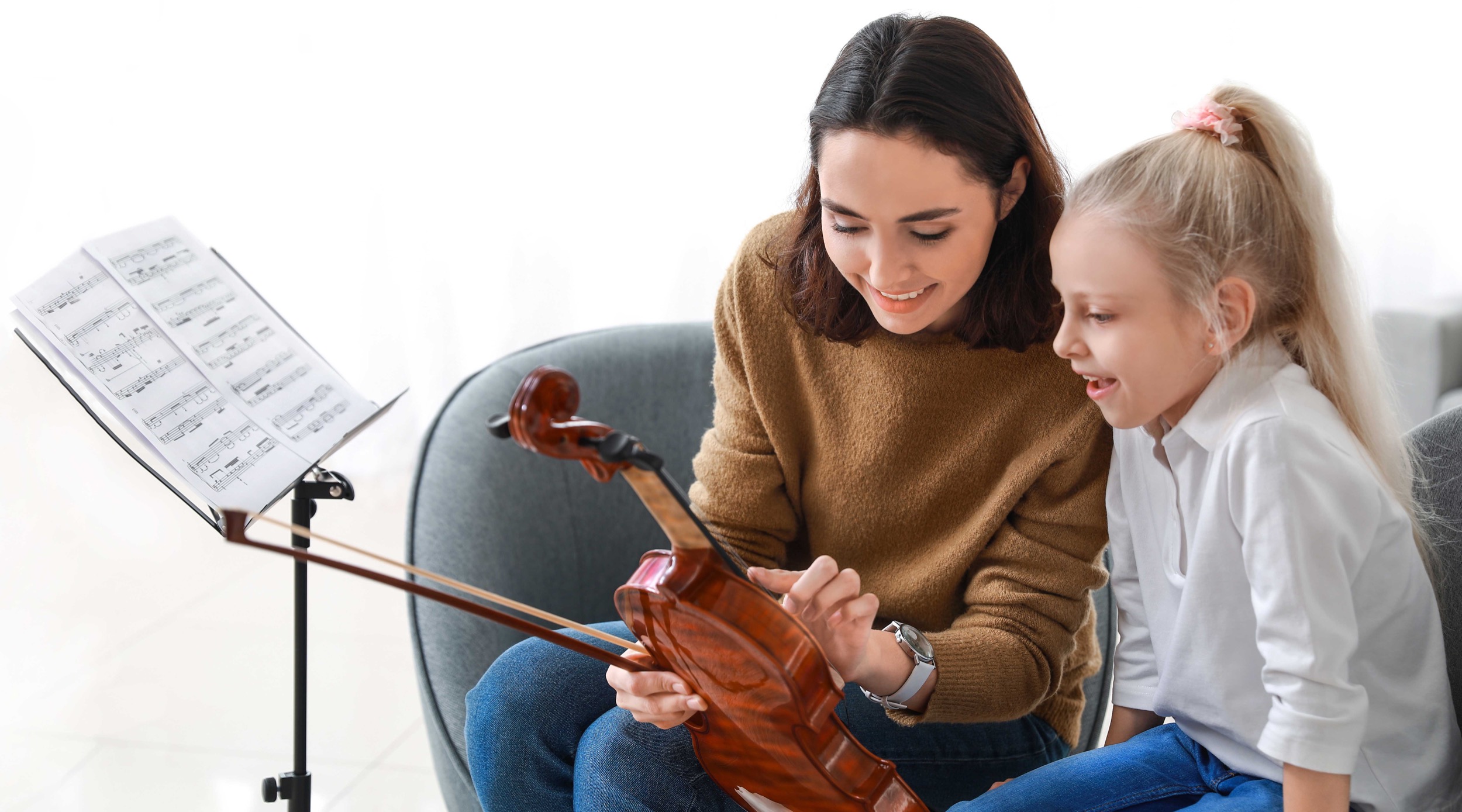 mother and daughter smiling as they inspect a violin together