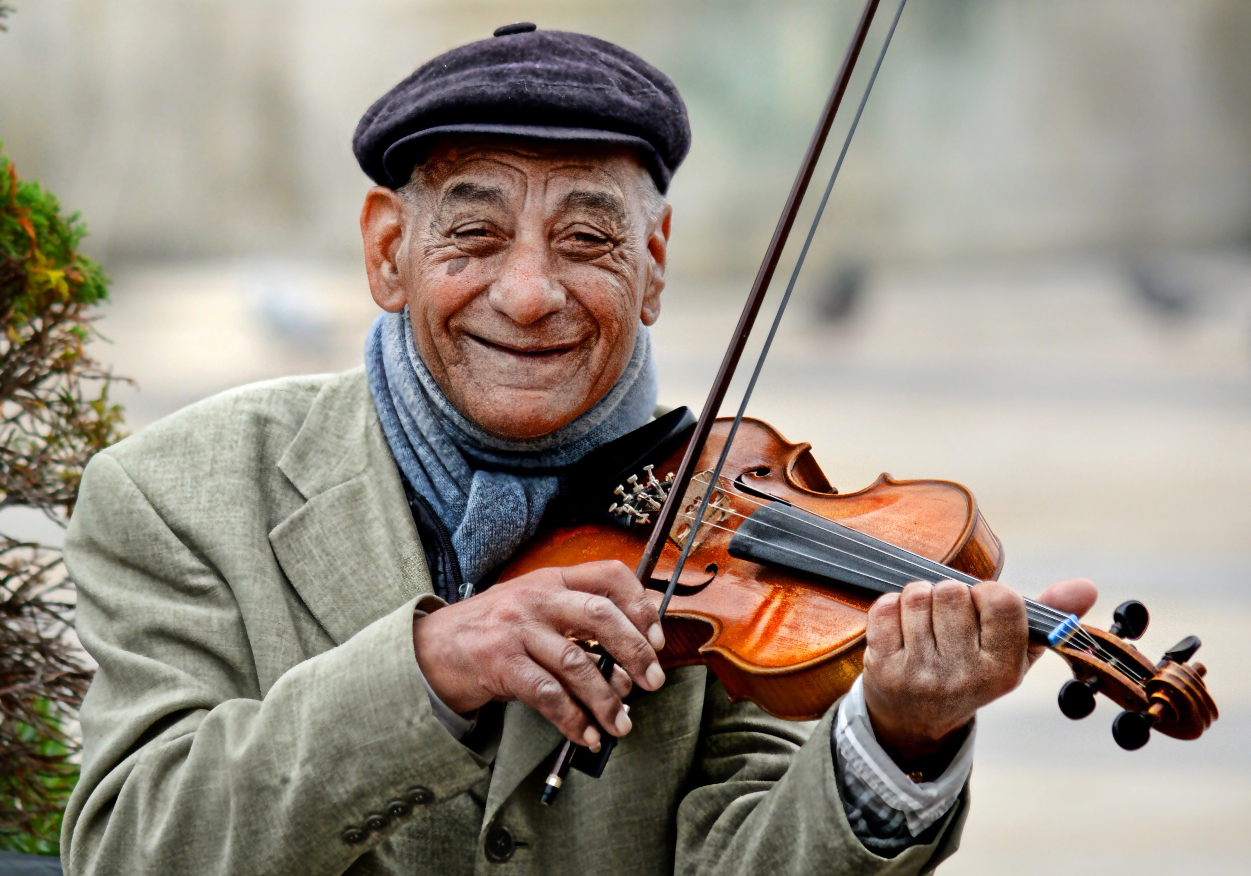 Old man with wrinkled face and smiling while playing the violin