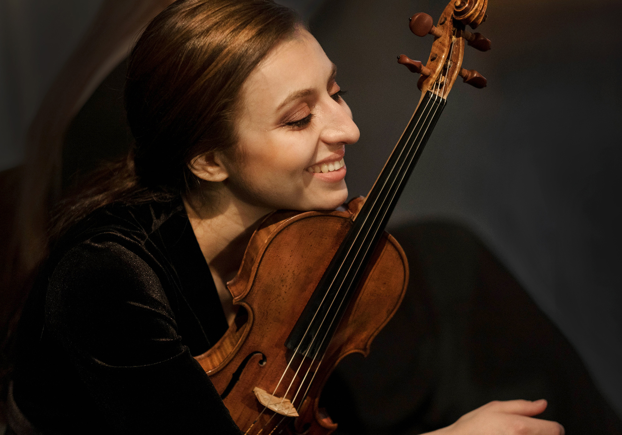 Young white woman violinist holding her violin and smiling