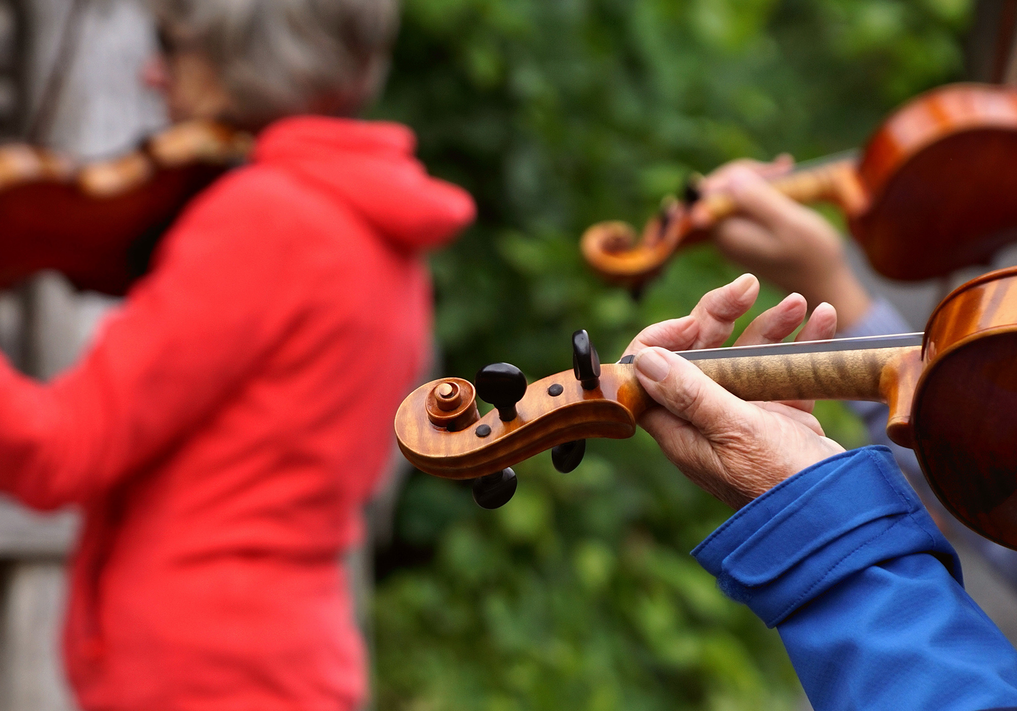 Older white people playing violin together outside