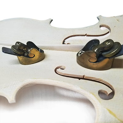 unvarnished violin plate being carved with planers