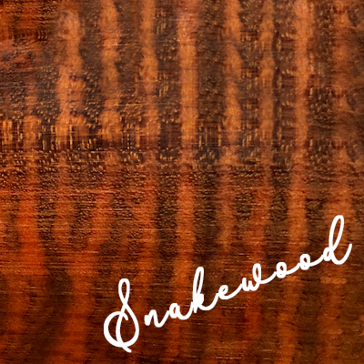 Label reads Snakewood; Deep reddish brown wood with nearly black spots in a scale pattern