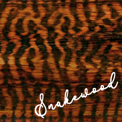 Label reads Snakewood; Deep reddish brown wood with nearly black spots in a scale pattern