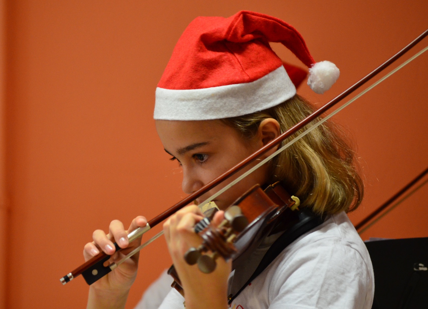 Little girl wearing a Santa hat playing violin