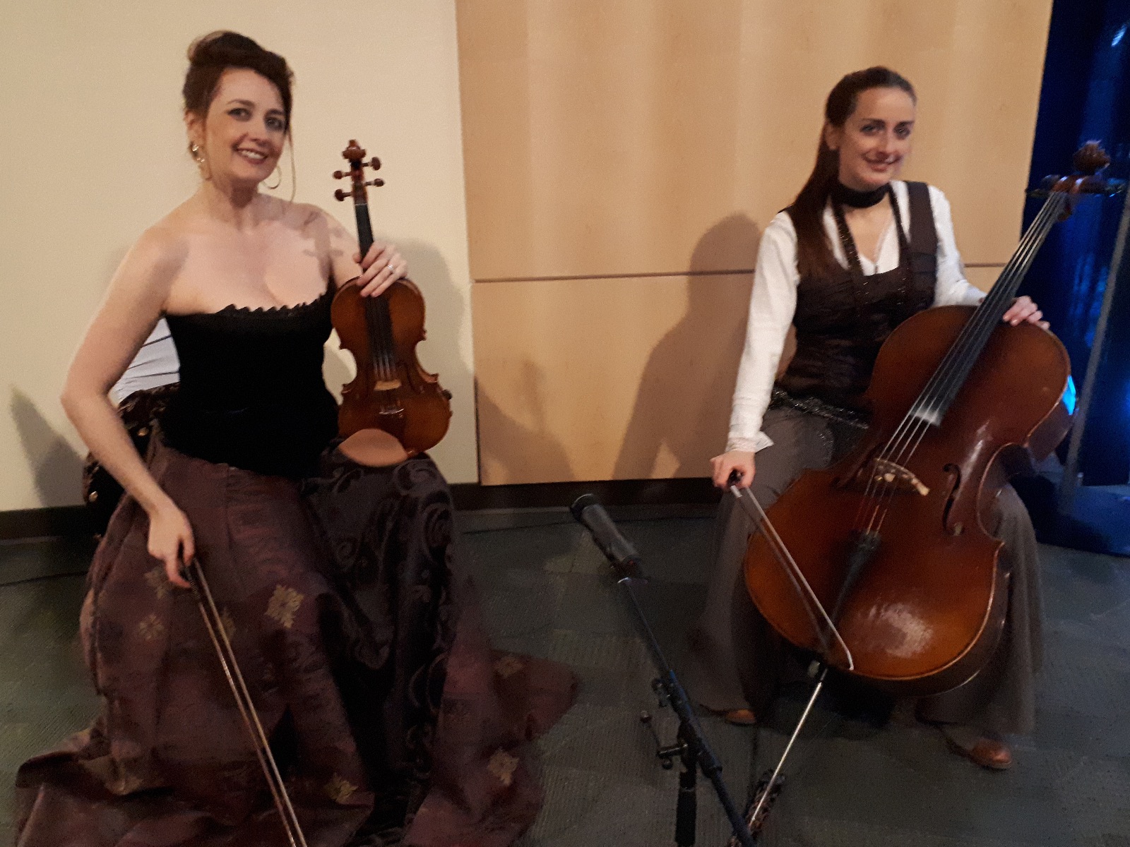 Rhiannon in a big brown skirt and corset and Laure in a similar pirate costume with their violin and cello