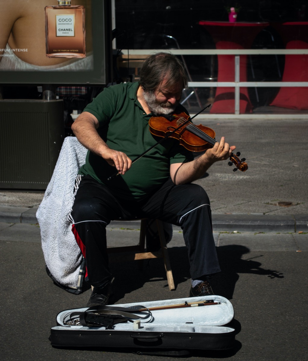 Heavy set older man playing violin with his case open