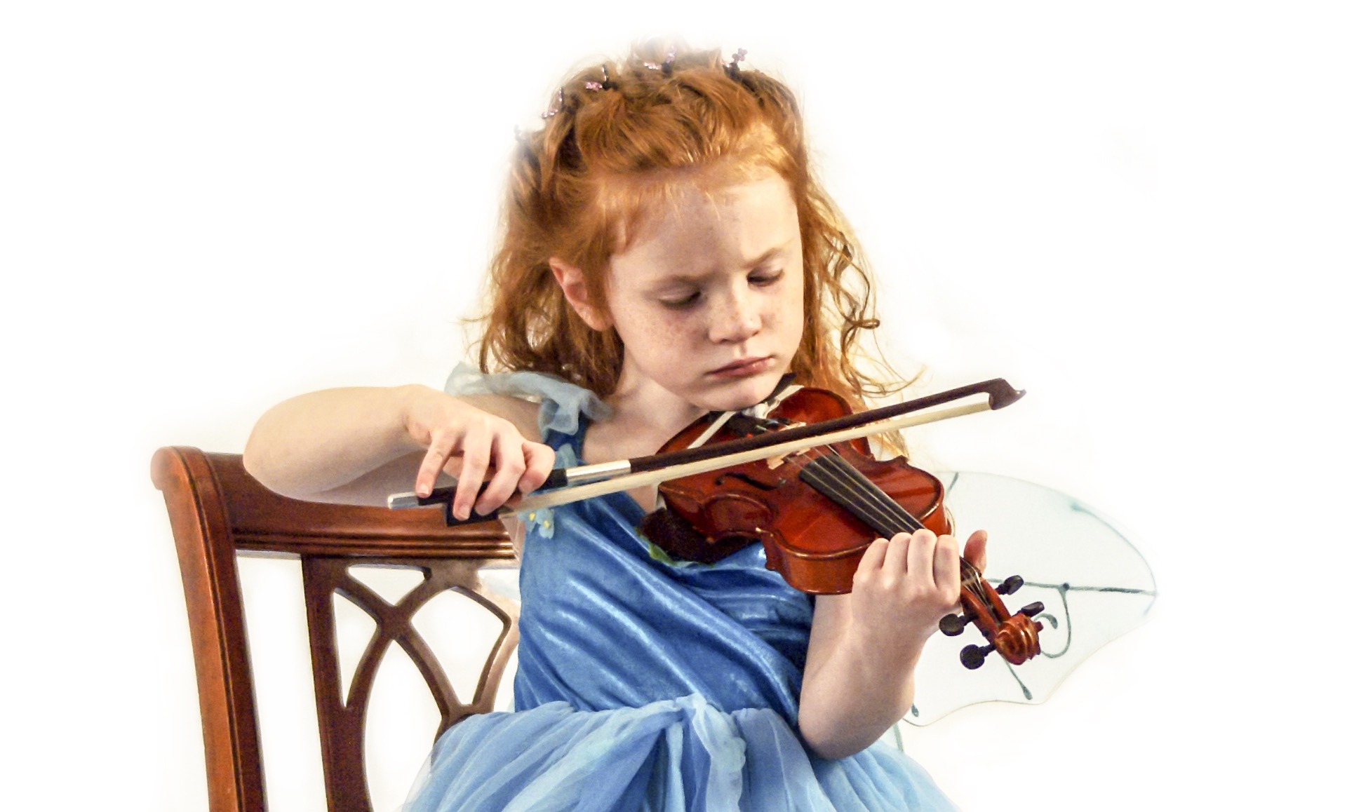 little redheaded girl in a blue fairy costume playing violin