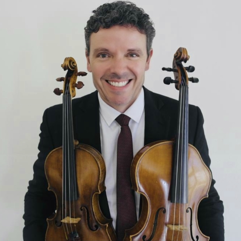 Antonio in a suit holding his violin and viola
